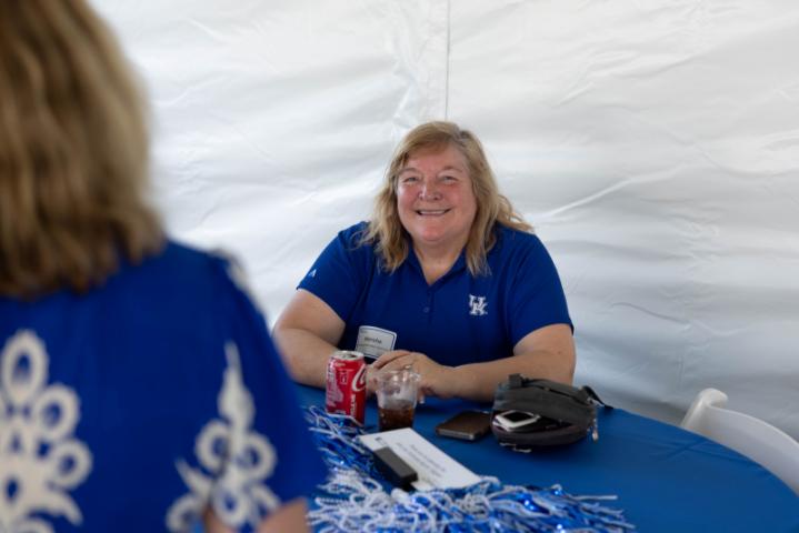 Alumni smiling at camera in blue polo at table