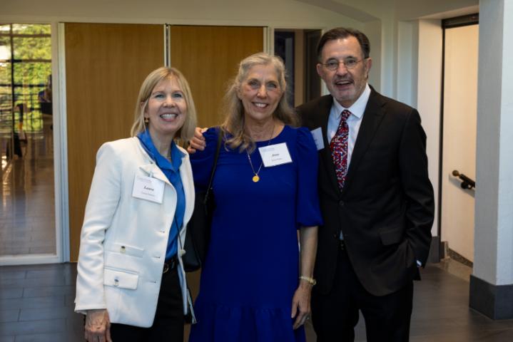 Three people posing together and smiling at event.