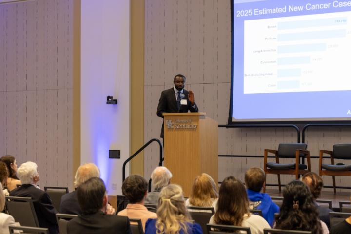 Man presenting cancer statistics slide to audience.