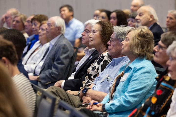 Audience members seated and listening intently during presentation.