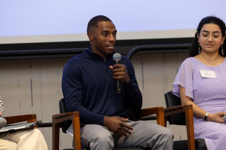 Man in navy Lunsford Scholars shirt speaking into microphone.