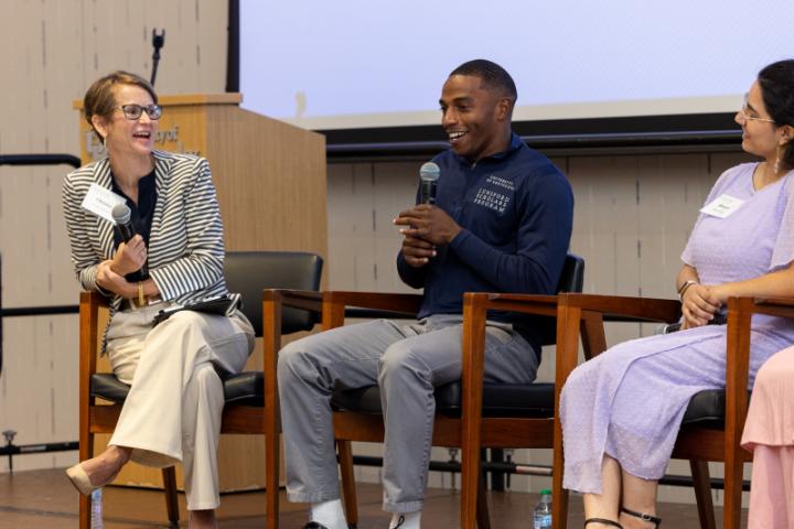 Panelist in navy shirt smiling while speaking with moderator.