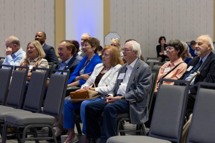 Attendees in front row smiling and laughing during event.