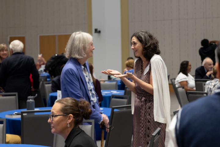 Two women standing and talking animatedly in event space.