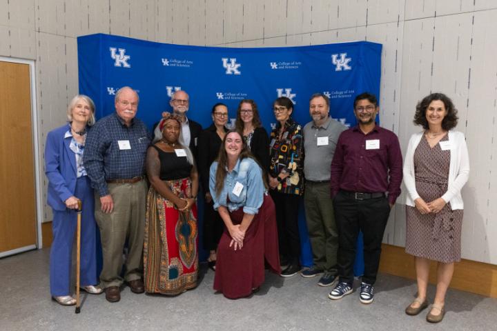 Large group of 11 people posing together in front of UK A&S backdrop.