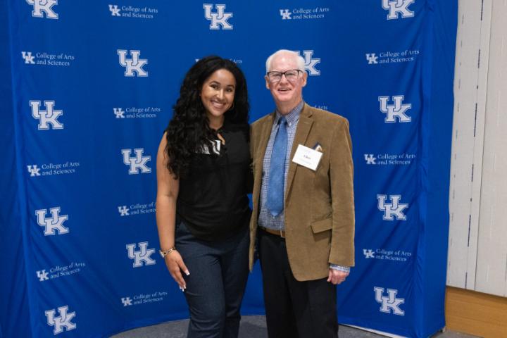 Two people smiling side by side in front of UK A&S backdrop.