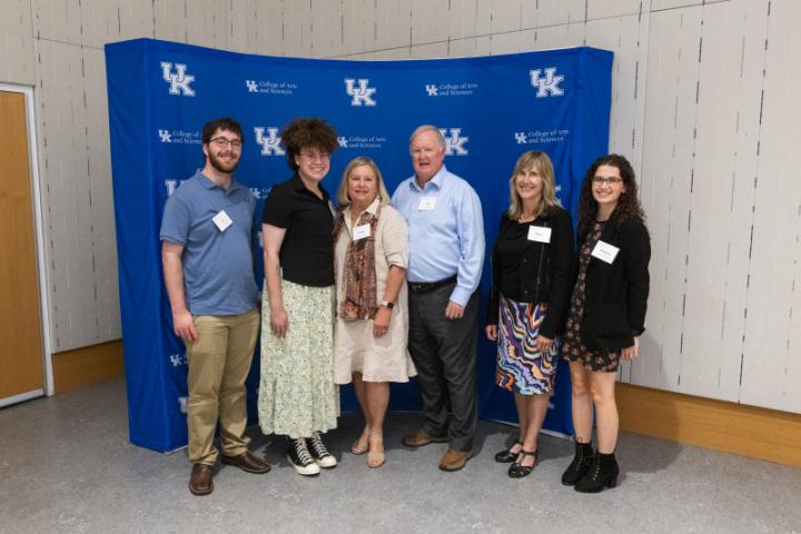 Group of six posing in front of UK A&S backdrop.