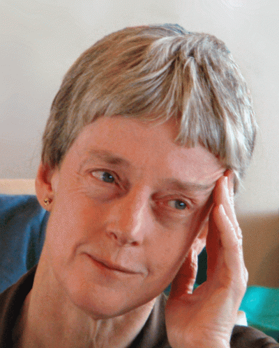 A woman with short hair rests her hand on her face.