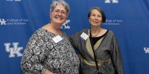 Two attendees pose in front of a backdrop