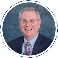 Steven Yates in a navy suit and multicolor tie