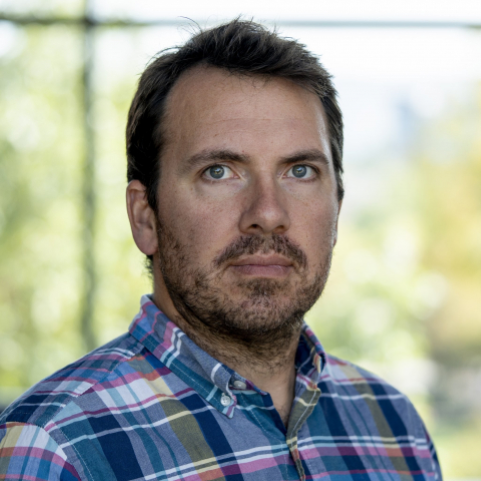 Pictured is Dr. Jesse Lasky wearing a plaid collared navy with pink and yellow button up shirt.